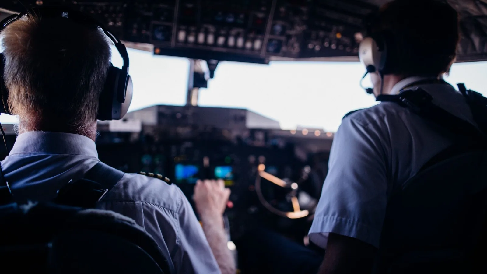 Pilotos em uniforme usando headset no cockpit de uma aeronave durante o voo