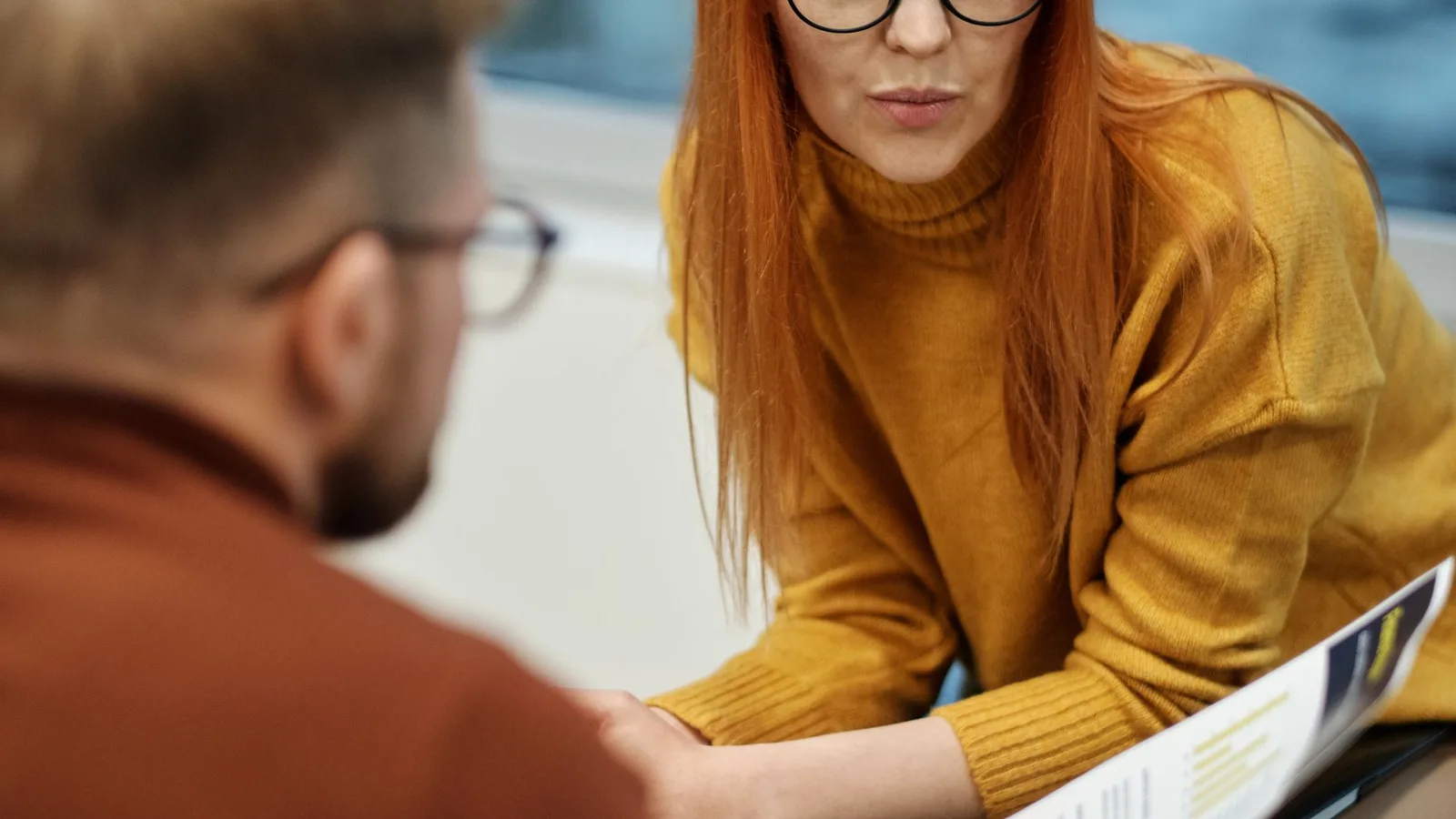 Profissional de meia-idade em reunião de trabalho, atento e confiante, usando aparelho auditivo discreto