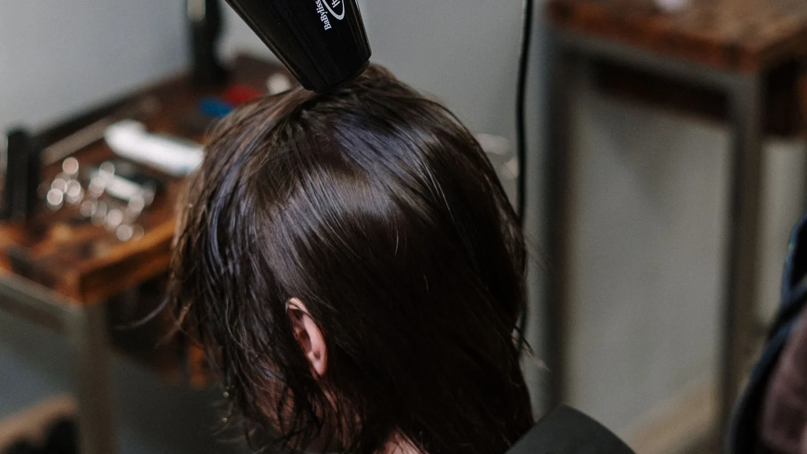 Cabeleireiro secando cabelo de cliente com secador em salão de beleza