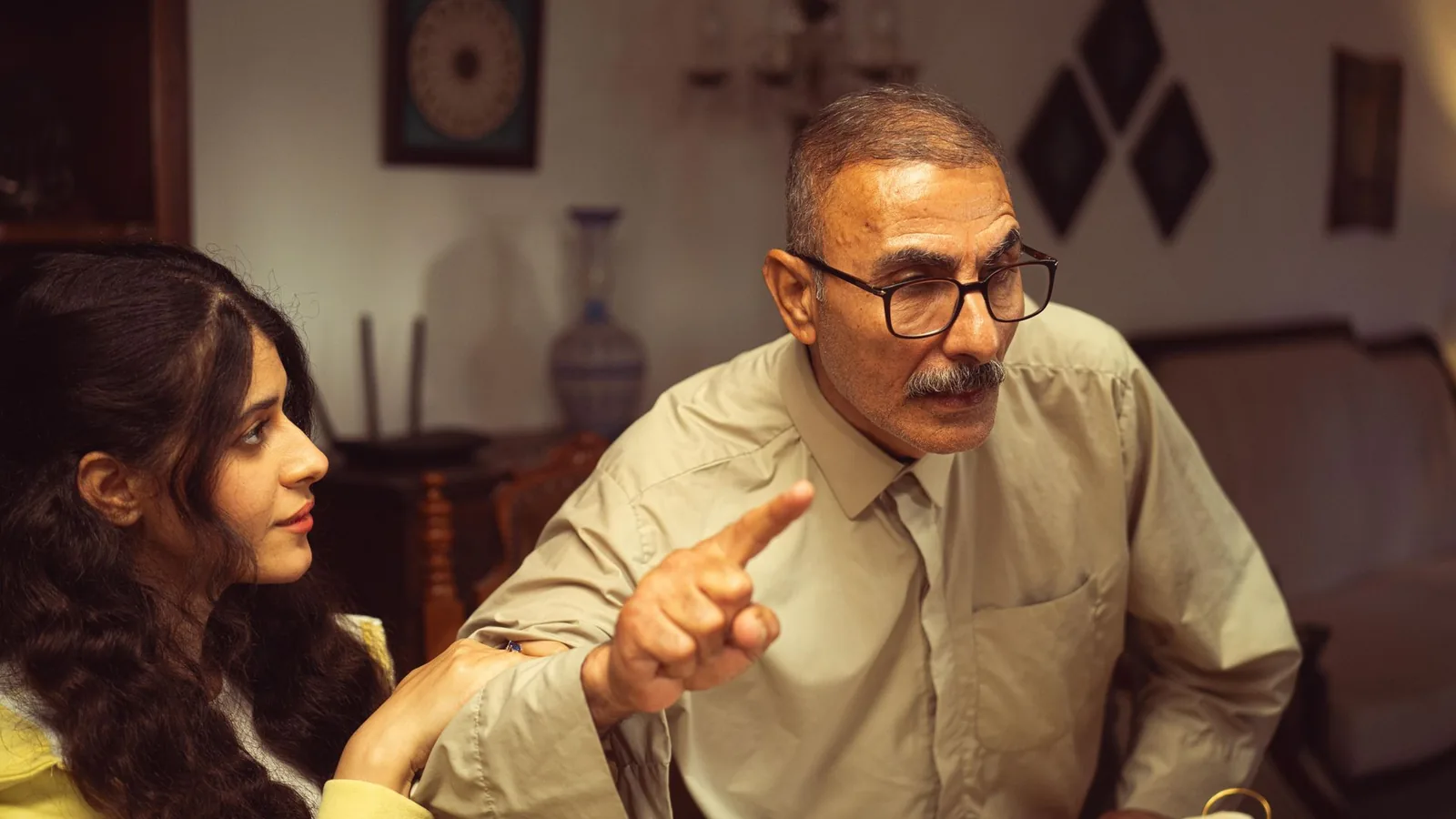 Pai e filha em conversa séria e afetuosa em casa, representando o diálogo sobre aceitar usar aparelho auditivo