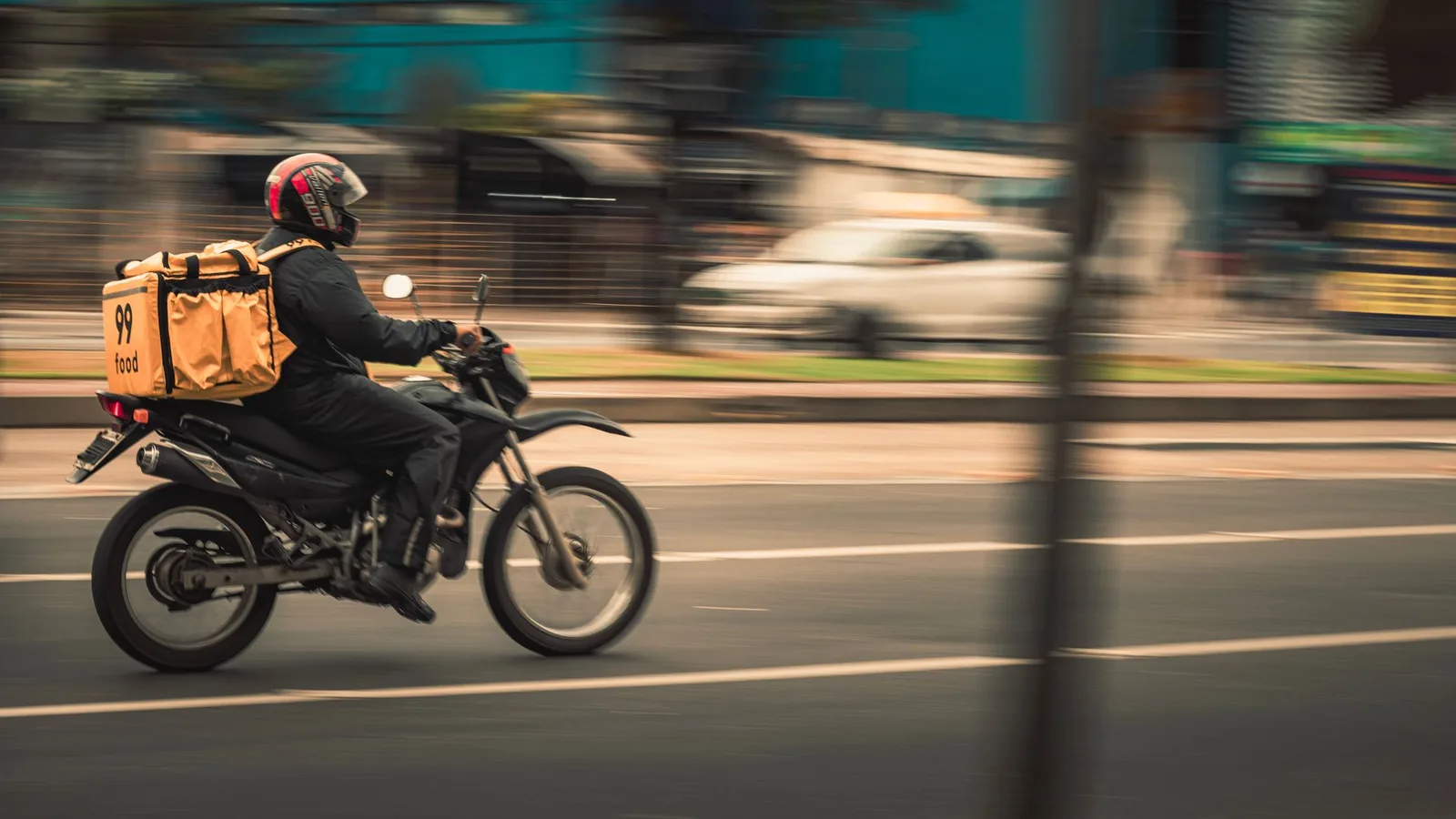 Entregador de aplicativo em moto usando capacete e fone de ouvido em Fortaleza