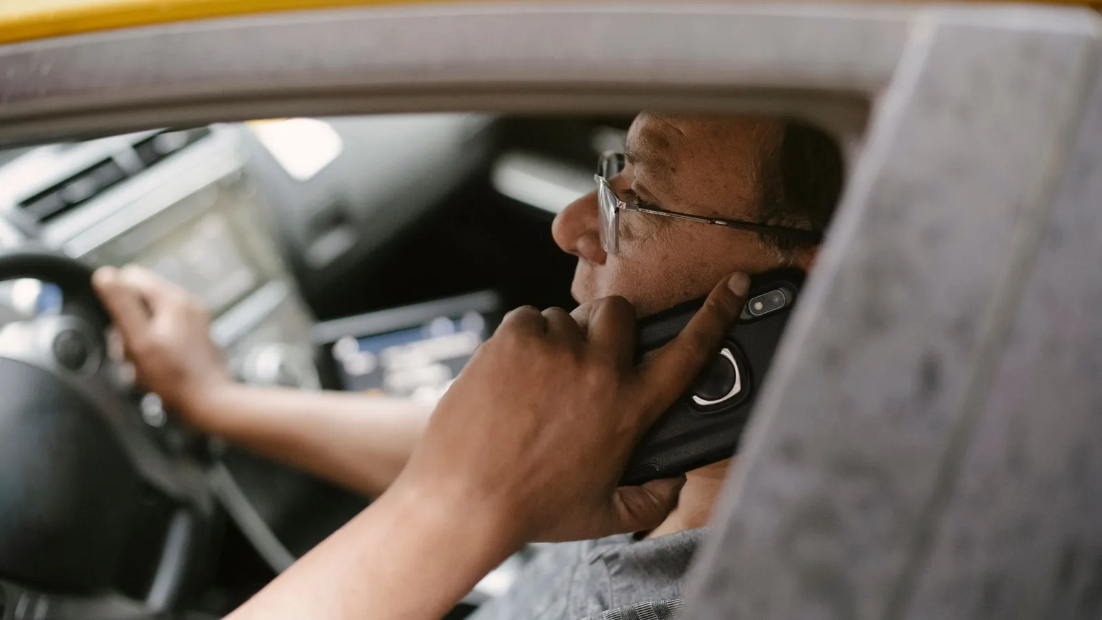 Motorista de aplicativo ao volante usando fone de ouvido e atento ao trânsito