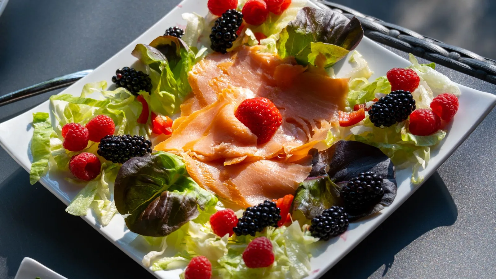 Prato saudável com peixe, frutas cítricas e vegetais folhosos, representando alimentação e saúde auditiva