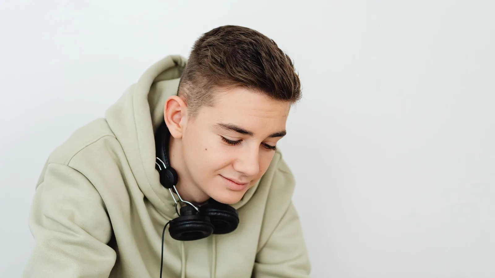 Jovem usando fone de ouvido intra-auricular enquanto estuda em ambiente urbano, celular na mão