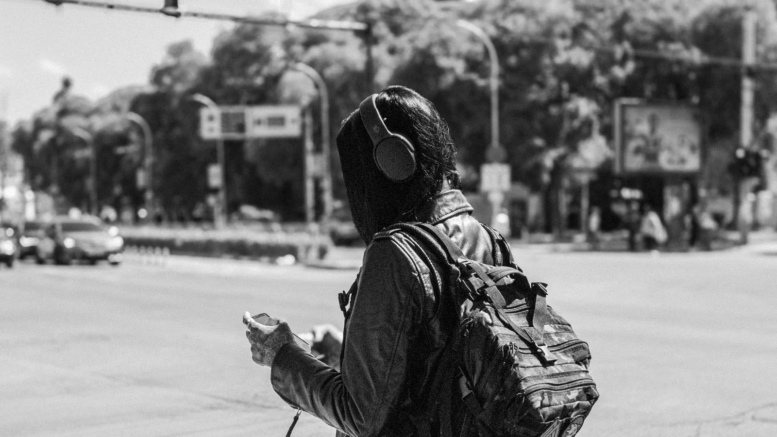 Pessoa usando fones de ouvido em ambiente urbano com trânsito ao fundo, expressão de desconforto, destacando o ruído excessivo