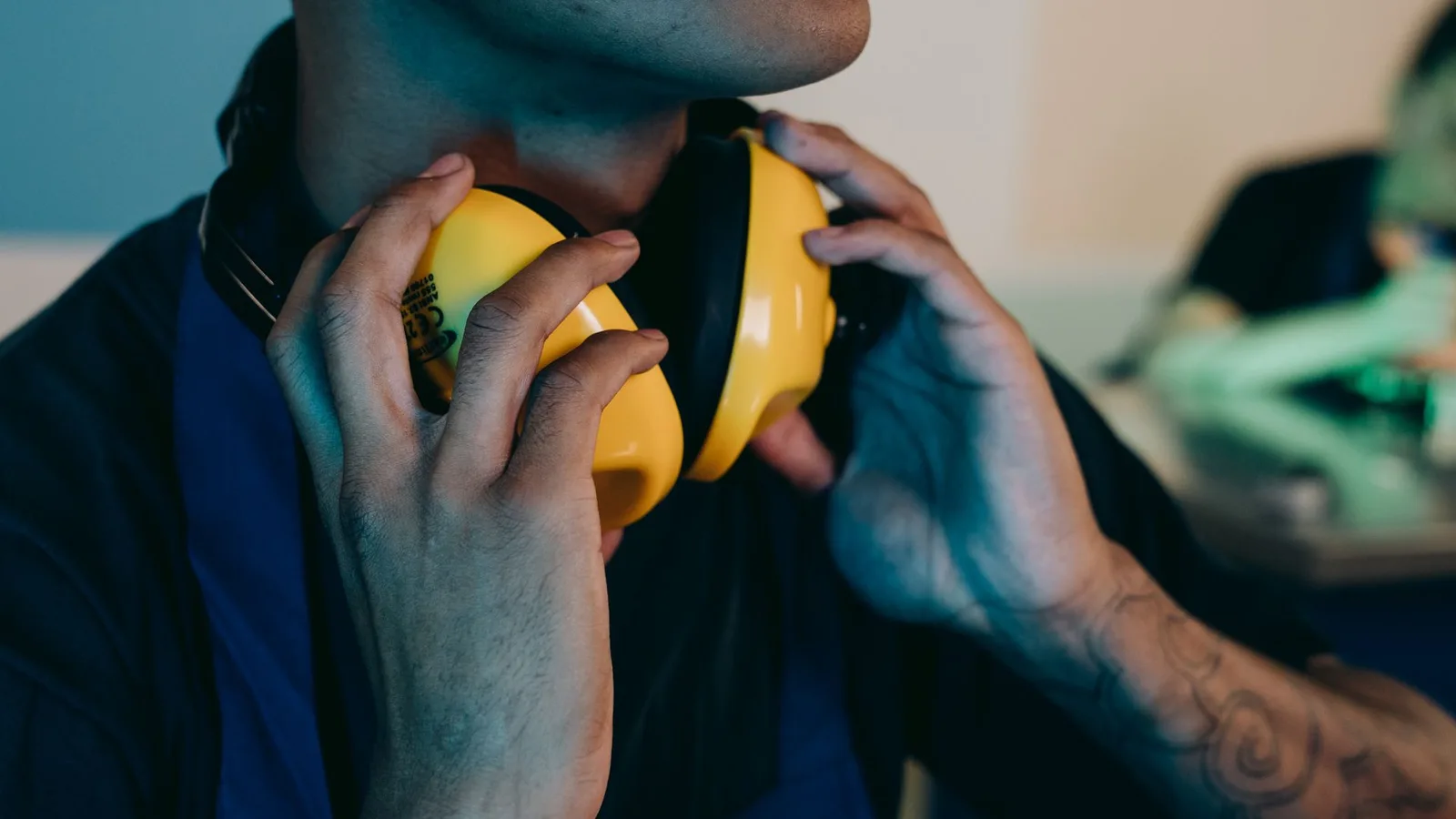Trabalhador colocando protetor auricular tipo concha em ambiente profissional