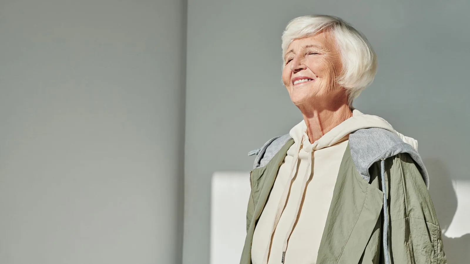 Senhora idosa sorridente, elegante, representando qualidade de vida ao considerar a troca do aparelho auditivo