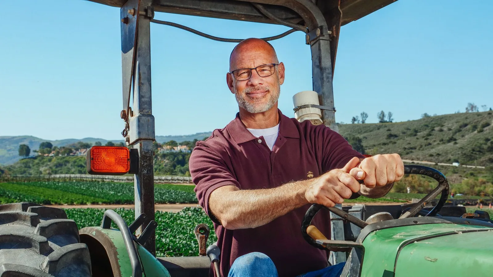 Trabalhador rural operando trator agrícola em plantação