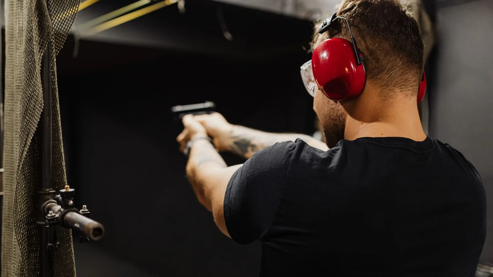 Homem usando abafador de proteção auricular e óculos de segurança durante treinamento de tiro em estande