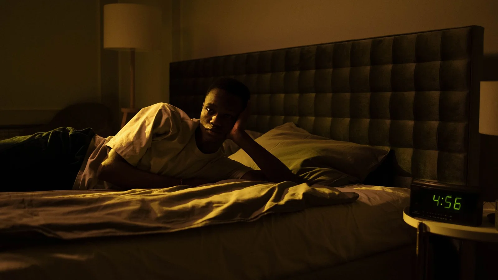 Pessoa idosa deitada na cama com expressão tranquila em quarto escuro, representando zumbido noturno