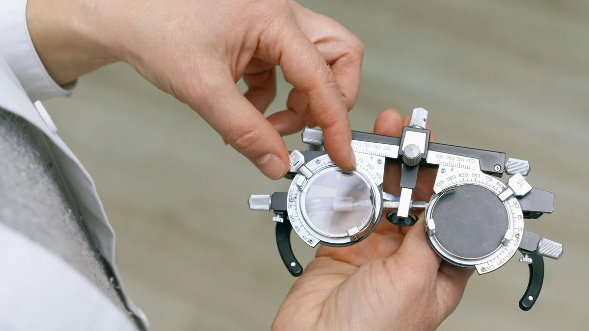 Profissional medindo lentes de óculos em lensômetro na ótica