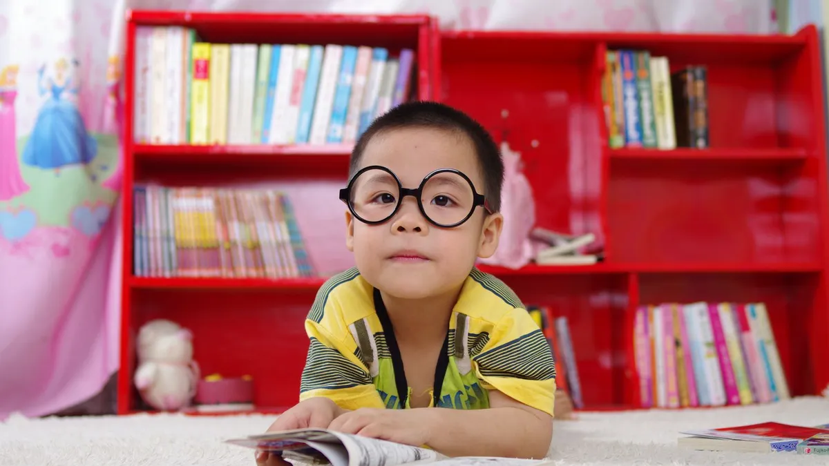 Menino com óculos perto de uma estante de livros