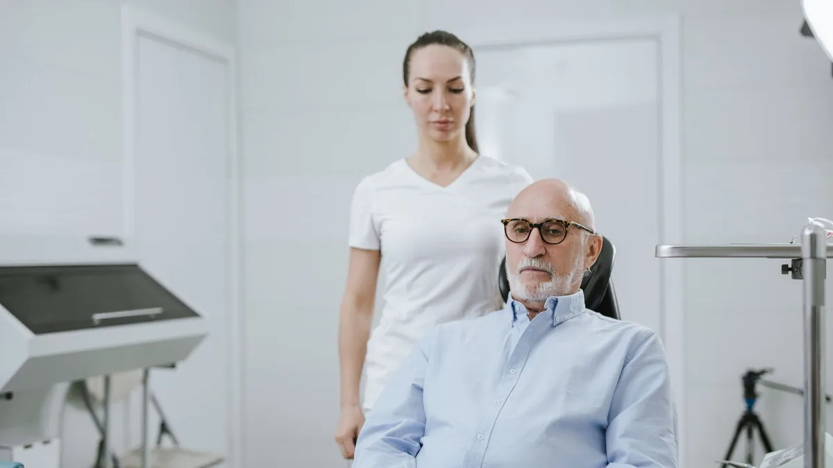 Pessoa idosa segurando uma cartela de teste de visão com linhas onduladas, representando distorção visual da DMRI