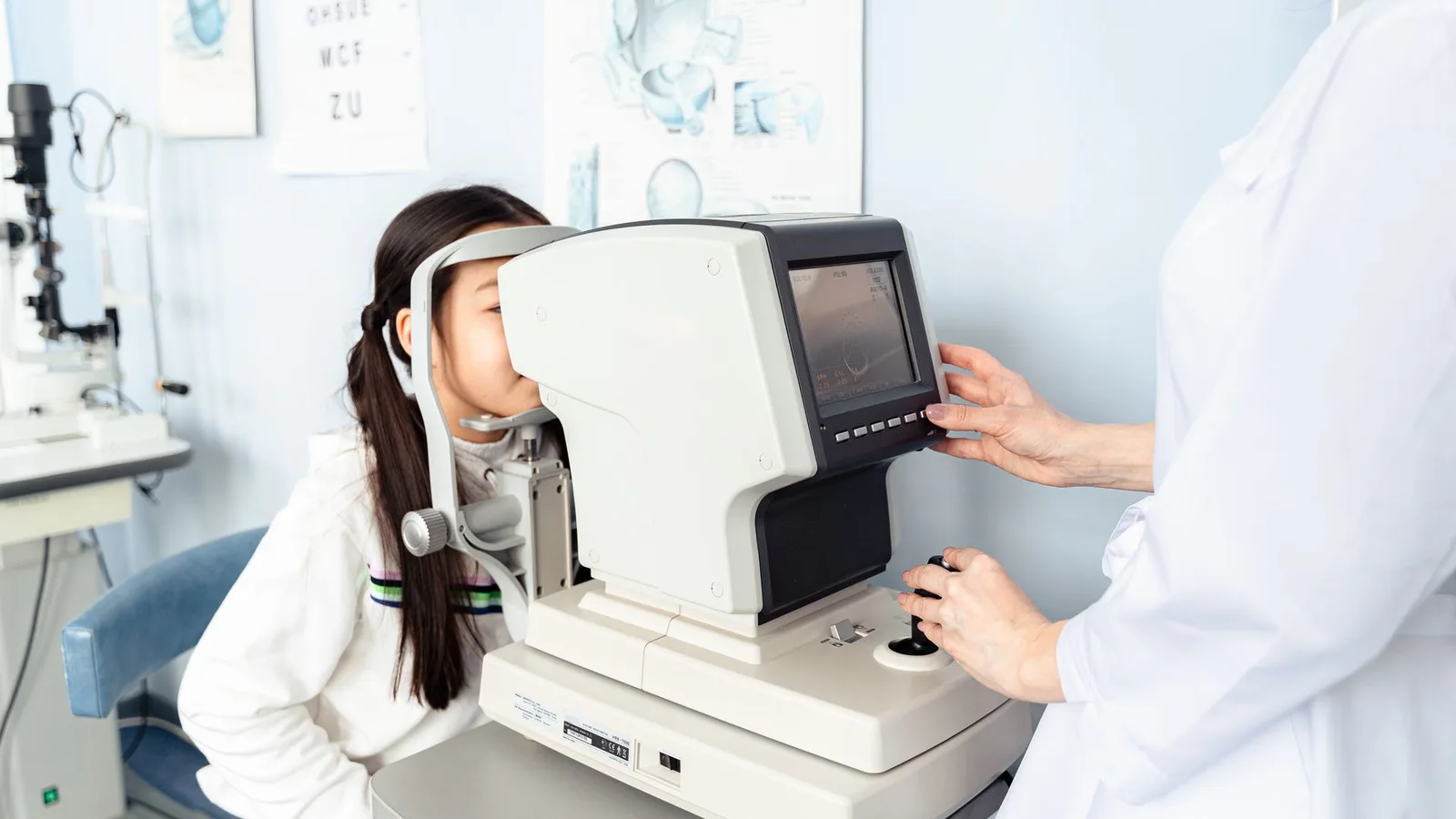 Criança sentada em consultório oftalmológico realizando exame de vista com profissional de saúde visual