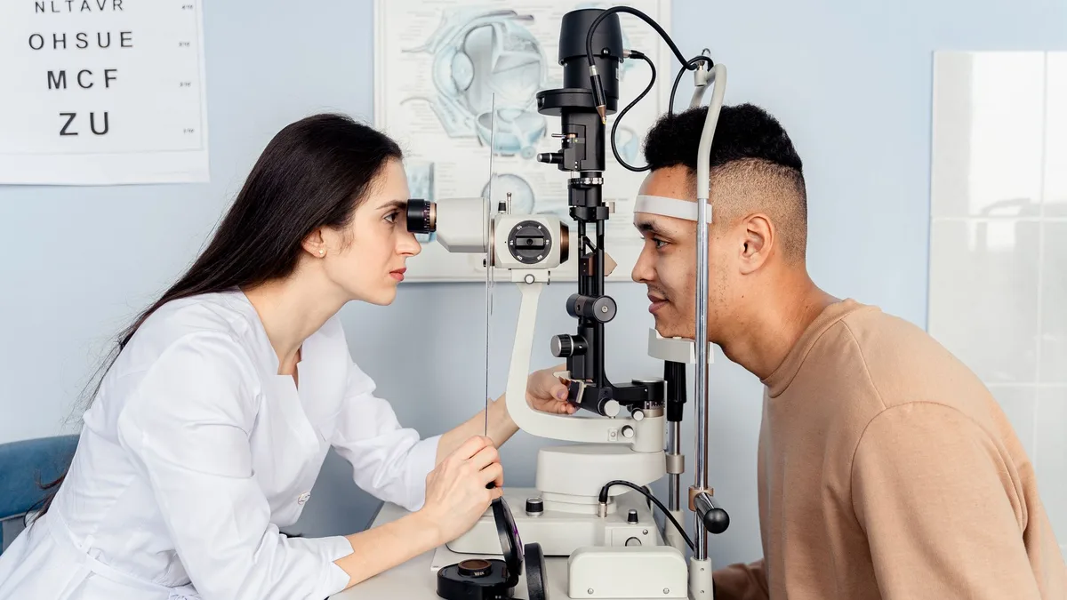 Oftalmologista utilizando lâmpada de fenda para examinar os olhos de paciente idosa