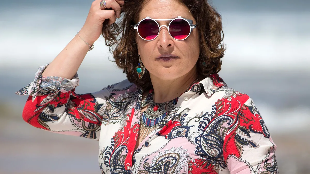 Óculos de sol com grau apoiados na areia da praia com mar ao fundo