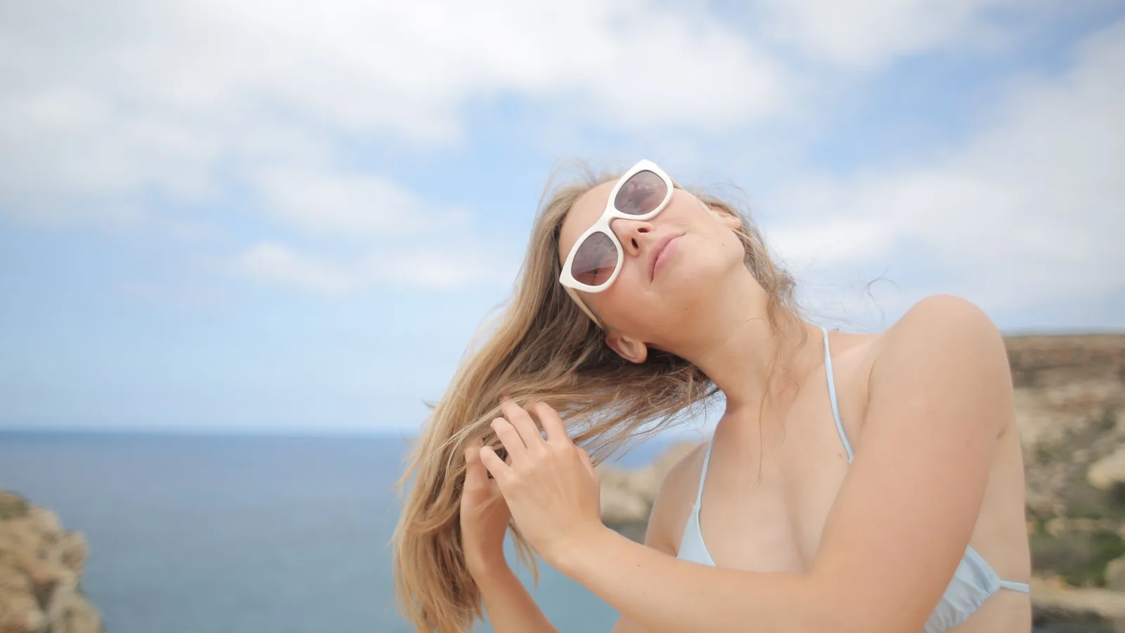 Mulher usando óculos de sol na praia em Fortaleza, protegendo os olhos do sol e da água