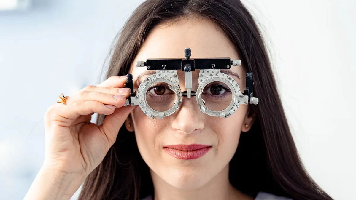Especialista examinando os olhos de paciente com lâmpada de fenda em consulta de adaptação