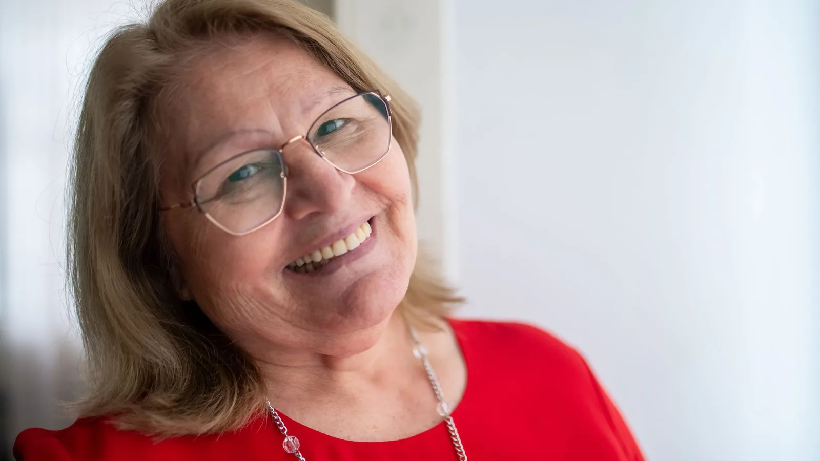 Idoso feliz sorrindo usando óculos de grau novos em consultório oftalmológico