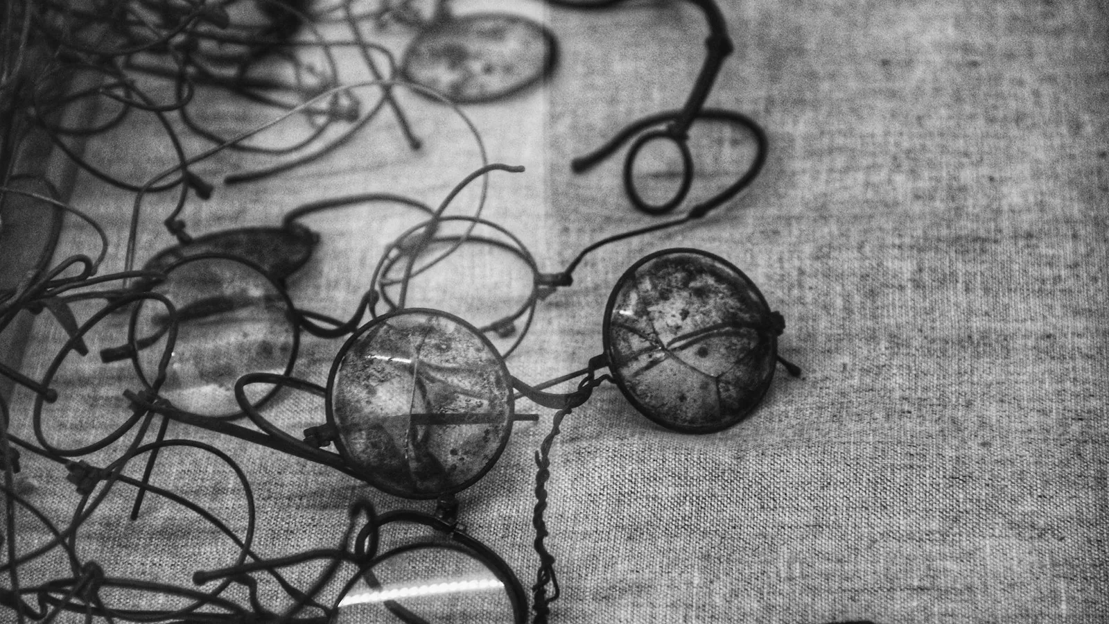 Pessoa segurando óculos de grau usado com lentes desgastadas sobre fundo desfocado