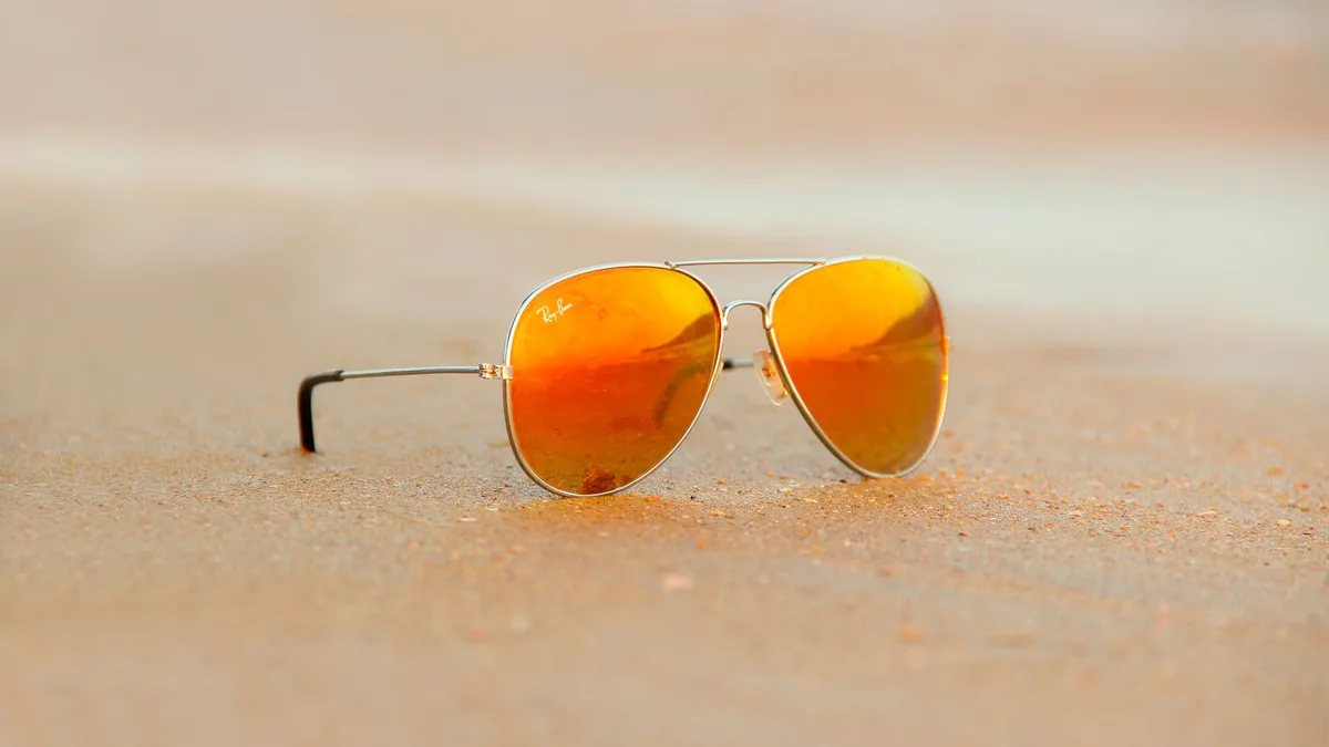 Óculos de sol estilo aviador apoiados na areia da praia
