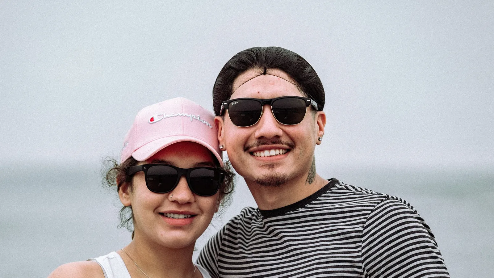 Casal sorrindo usando óculos de sol em um passeio