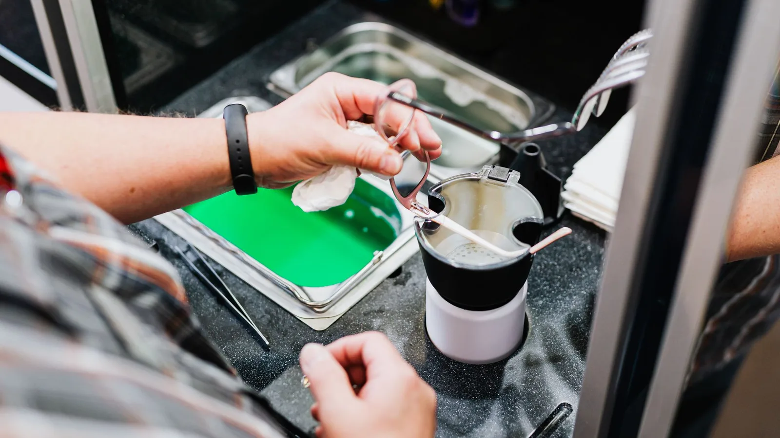 Óculos de grau sobre mesa com flanela de microfibra e spray de limpeza