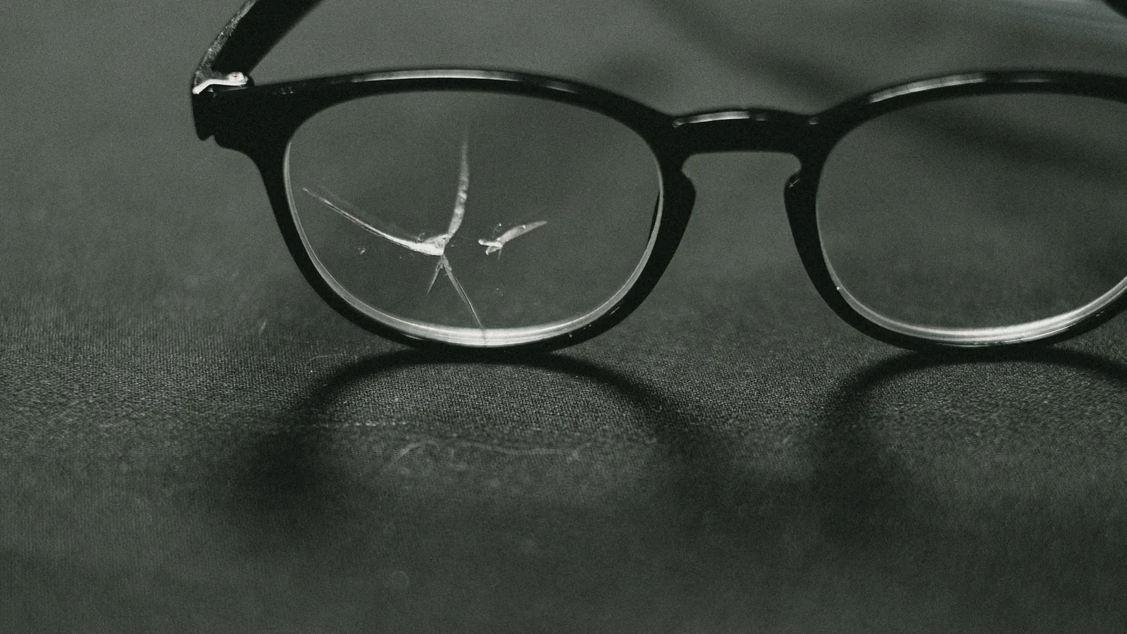 óculos de grau sobre superfície com lentes e armação visíveis, mostrando sinais de uso e desgaste