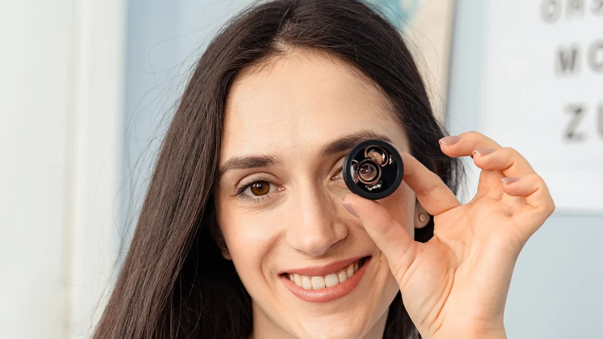 Mulher segurando lente de teste diante do olho com tabela de letras ao fundo