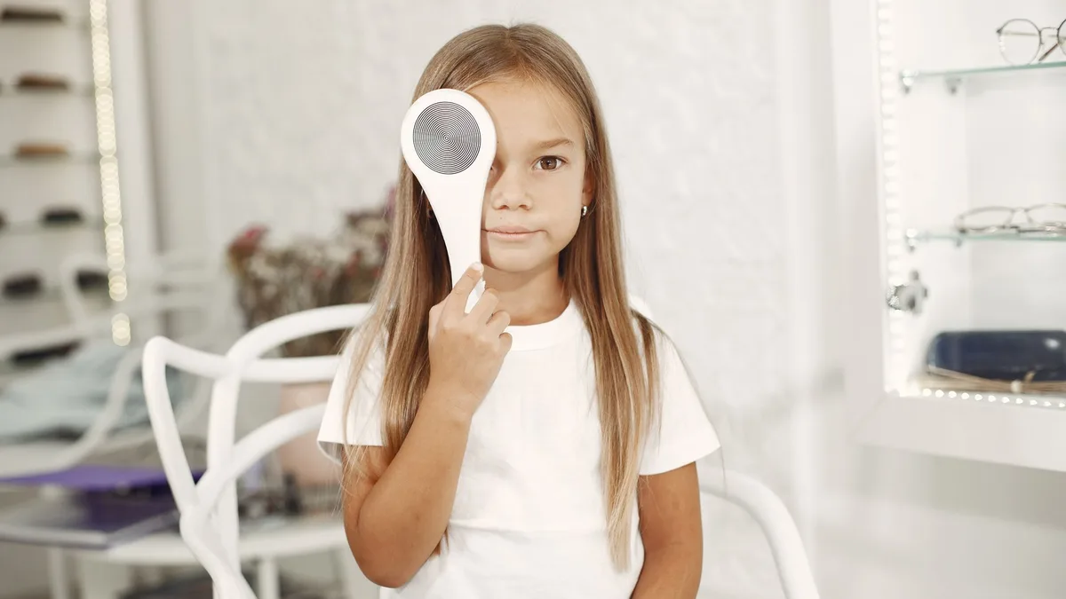 Criança brincando com tampão no olho enquanto desenha