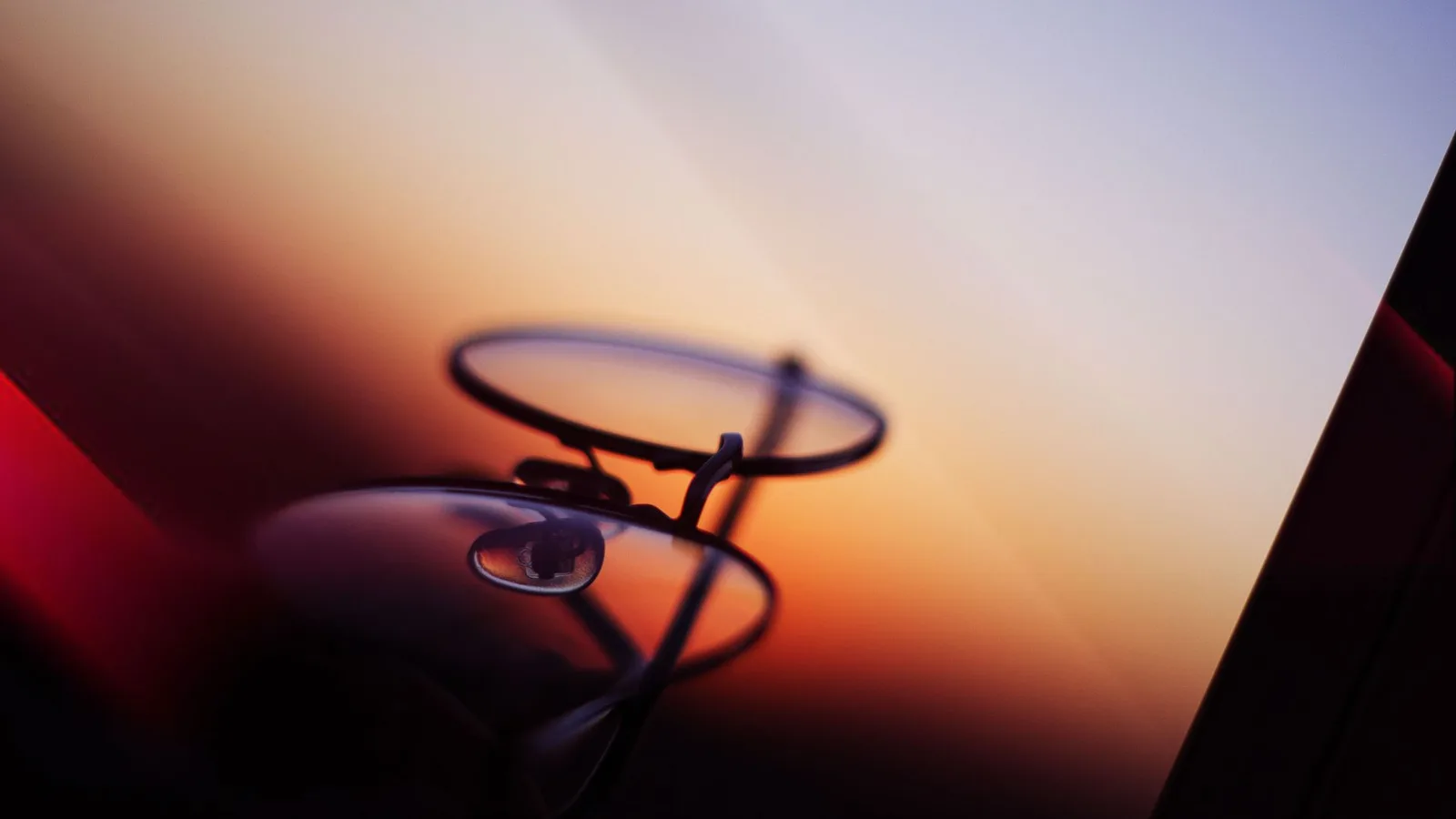 Pessoa segurando óculos com lentes antirreflexo, comparando a visão com e sem o tratamento